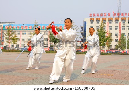 LUANNAN COUNTY - October 20: A group of old people is performing Taiji sword on the gym in the square, on October 20, 2011, LuanNan county, hebei province, China