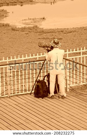 QINHUANGDAO CITY- JUNE 1: Male photographer was photographing in a wetland park, June 1, 2014, Qinghuangdao city, Hebei Province, China