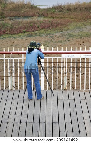 QINHUANGDAO CITY- JUNE 1: A female photographer was photographing in a wetland park, June 1, 2014, Qinghuangdao city, Hebei Province, China