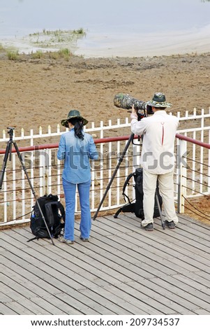 QINHUANGDAO CITY- JUNE 1: A man and a woman photographers photographing in a wetland park, June 1, 2014, Qinghuangdao city, Hebei Province, China