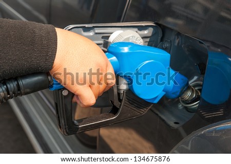 Male hand refilling the car with fuel in to the tank