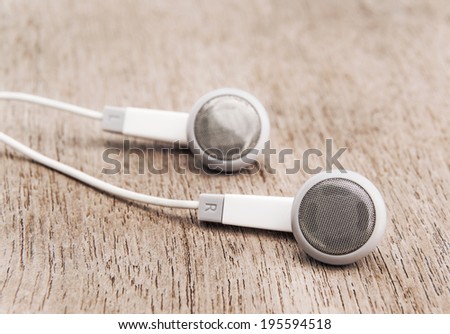 Modern portable audio earphones isolated on wood background