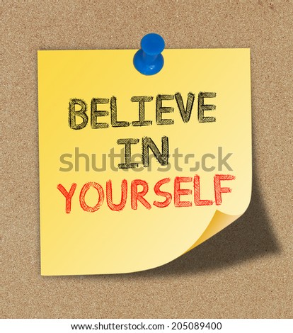 Believe In Yourself written on yellow note pinned on cork board background.