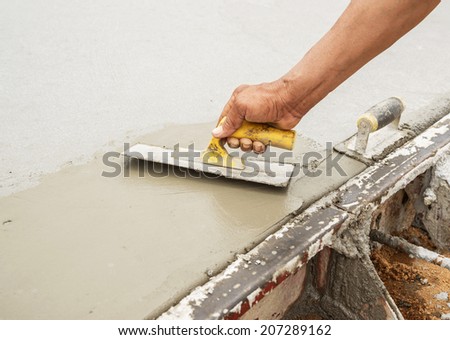 Workers hand using trowel with wet concrete, Construction road with cement. Selective focus.