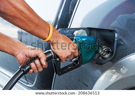 Man pumping gasoline fuel in car at gas station