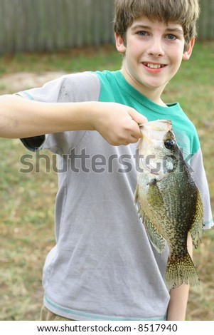 young boy holding fish he caught