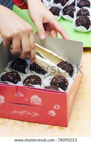 Fresh round chocolate cake put into box using cake holder