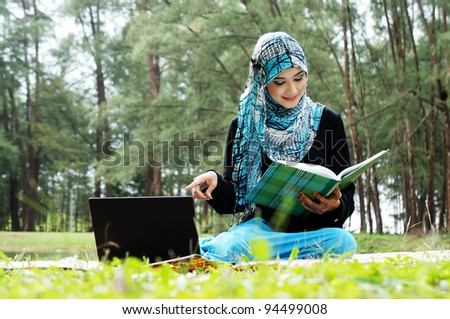 Beautiful muslim woman wearing scarf  with notebook at a lake garden
