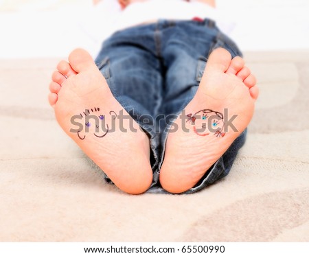 child\'s feet with funny smiling faces drawn on them