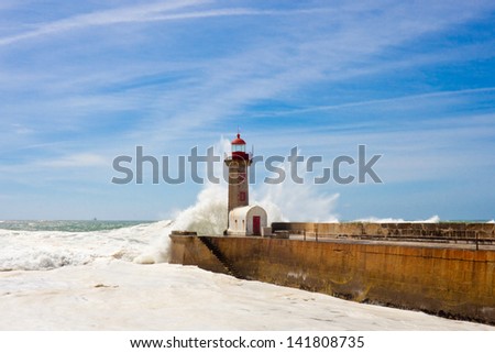 Waves over lighthouse in Porto on bright sunny day