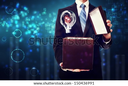 Business man opening box with an idea light bulb on blue technology background
