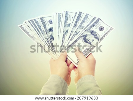Hand Displaying a Spread of Cash in a Vintage Light