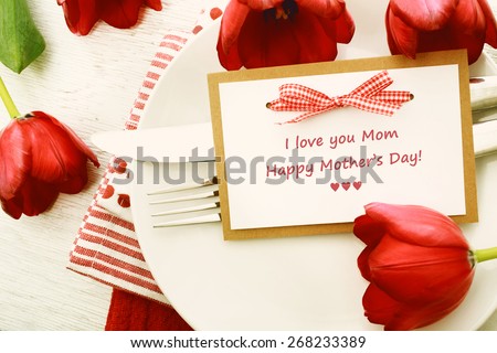 Dinner table setting with Mothers day message card and red tulips