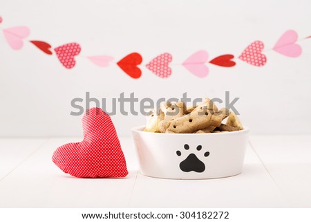Dog treats on a white bowl with a heart cushion with a garland of hearts