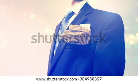 Businessman with wad of cash on blurred light background