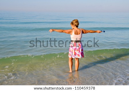 Attractive Middle Aged Woman Standing in the Ocean Holding Her Arms Out