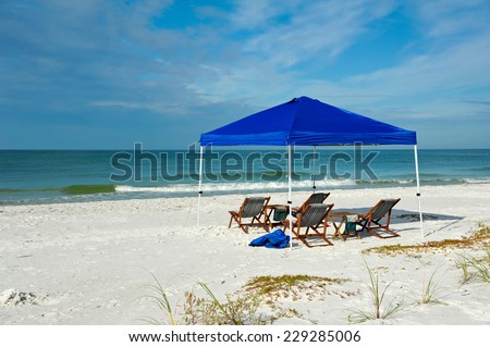 Portable Shelter with Lounge Chairs and Tables Set up on the Beach