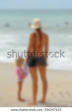Blur Background Image of a Mother and Daughter on the Beach watching swimmers in the Ocean