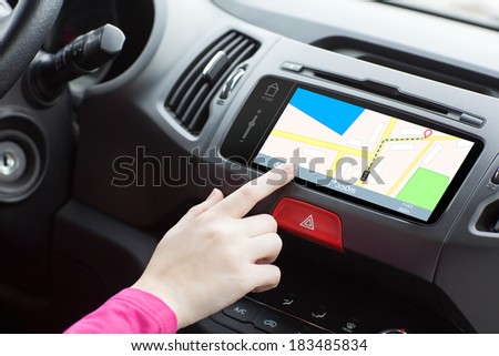 woman sitting in a car touching a GPS map on the dashboard.