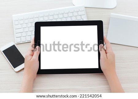 female hands holding a tablet with a isolated screen over a table in the office