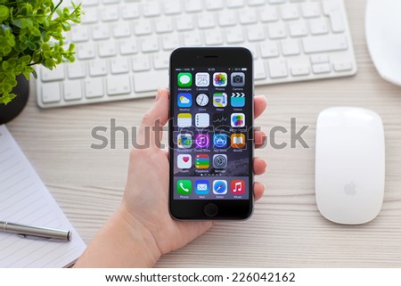 Alushta, Russia - October 25, 2014: Woman holding new phone iPhone 6 Space Gray over the table. iPhone 6 was created and developed by the Apple inc.