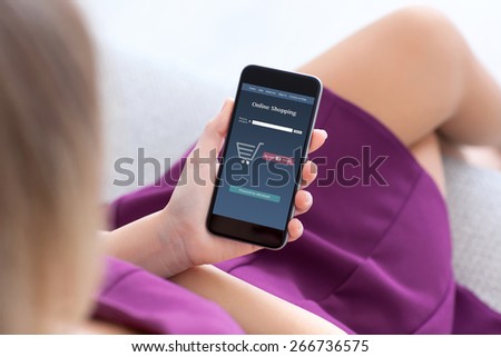girl in a purple dress sitting on the sofa and makes online shopping on a tablet