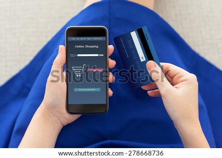 woman in a blue dress holding a phone with online shopping on the screen and credit card
