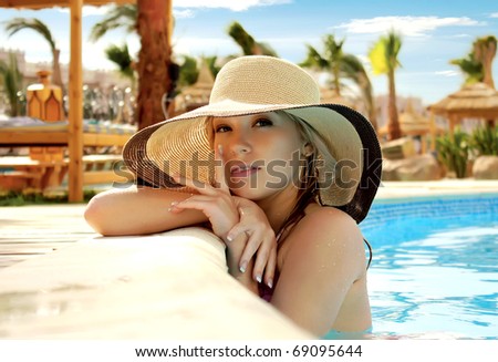 The smart blonde in a hat in pool of expensive hotel