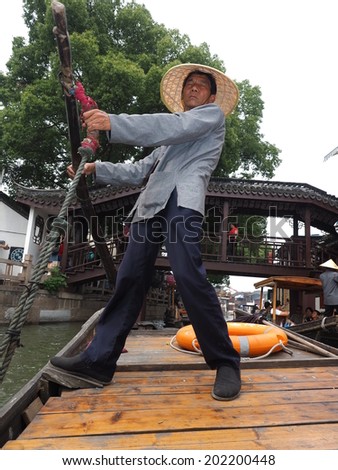 ZHUJIAJIAO, CHINA - MAY 21: Senior man transports recycling material in Chinese gondola on May 21, 2014 in Shanghai. Zhujiajiao is a well-known ancient water village  as Shanghai\'s version of Venice.