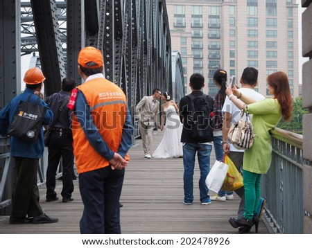SHANGHAI , CHINA - MAY 19: Unidentified Asian couple holding each other during a pre-wedding photograph session on a bridge in the center of Shanghai, May 19, 2014, Shanghai, China