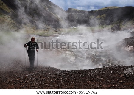 Young woman hiking with trekking sticks in geothermal area, Iceland