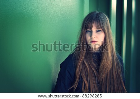 closeup fashion portrait of beautiful young woman posing over the green metal wall
