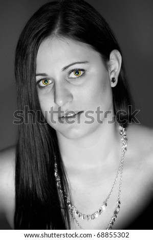 fashion black and white portrait of beautiful young woman posing over the wall. eyes in color like vampire