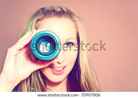 Attractive young woman holding camera lens like it was spyglass