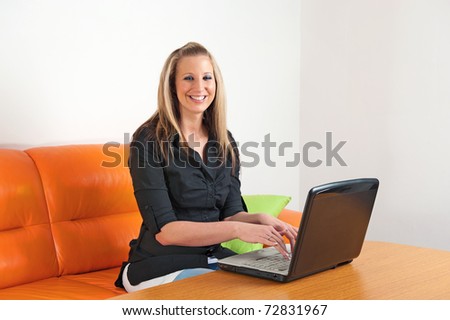 Attractive smiling young woman sitting at home using a laptop