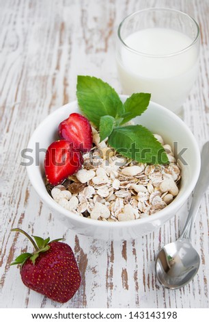 A bowl of cereal with strawberries and  milk