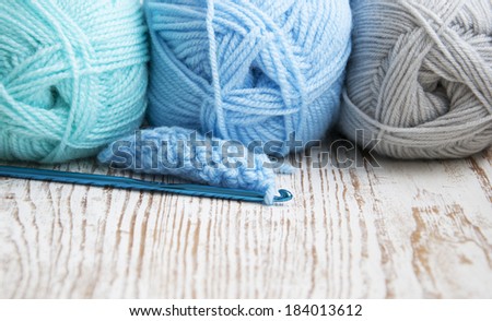 Crochet hook and knitting yarns on a wooden background