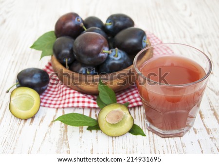 Glass with a Plum juice and fresh plums on a wooden background