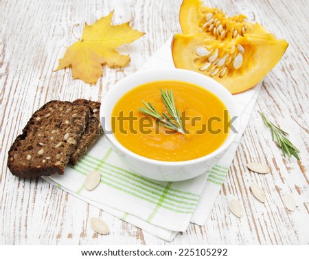 bowl with pumpkin soup and bread on a wooden background