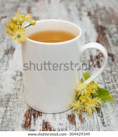 Cup of herbal tea with linden flowers on a old wooden background