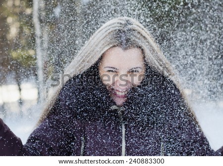 The The beautiful smiling woman has fun throwing snow upwards