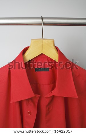 A Red men\'s dress shirt hanging on a hanger
