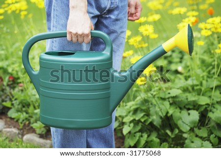 A Man holding a green plastic watering can in his hand.