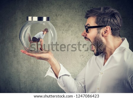 Side view of angry yelling man holding glass jar with captured woman for concept of relationship harassment  Foto stock © 