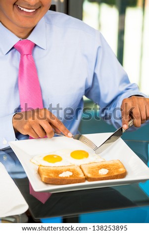 A close-up portrait of a happy businessman having a breakfast