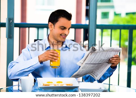Handsome businessman reading the morning paper and enjoying a healthy breakfast