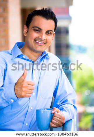 Good-looking businessman giving you a thumbs up - Isolated on a city background