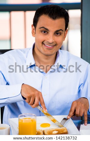 Portrait of a happy, young handsome man eating breakfast in his home, isolated on a city background
