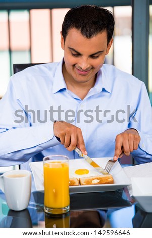 Portrait of a happy man eating a nutritious breakfast in his home, isolated on a city background