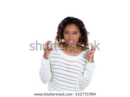 Closeup portrait of a young pretty woman crossing fingers wishing and praying for miracle, hoping for the best, isolated on white background copy space to left. Human emotions and facial expressions.